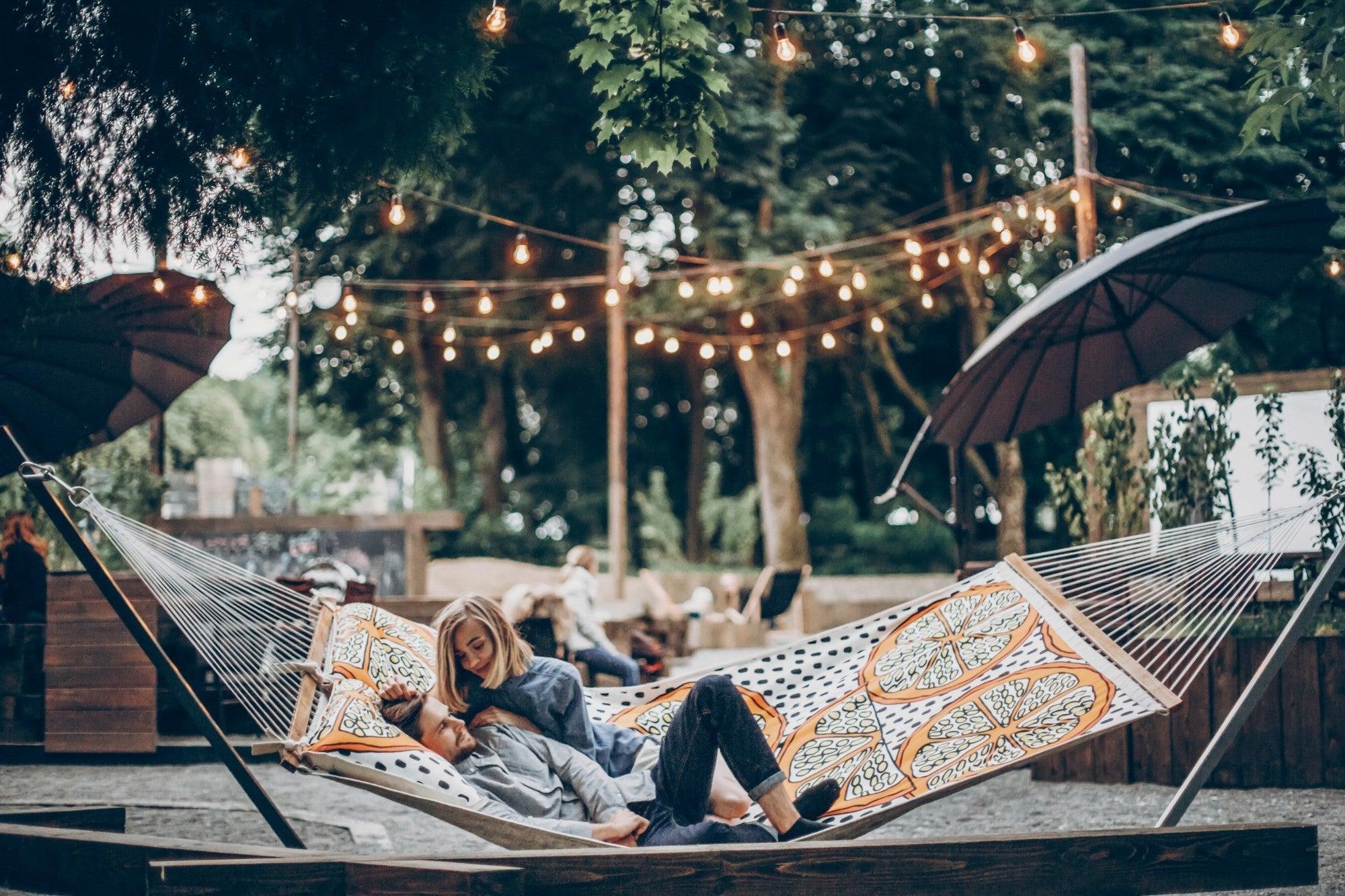 Paar entspannt in Hängematte mit Lichterketten im Garten