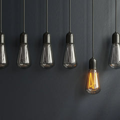 Industrielle Hängeleuchten mit LED-Filament im Vintage-Stil, eine Lampe warm beleuchtet vor dunkler Wand