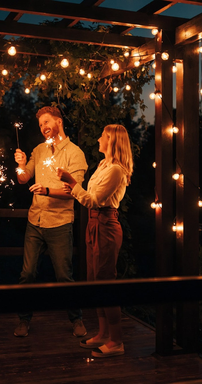 Freunde feiern unter Lichterketten im Garten bei Abendstimmung